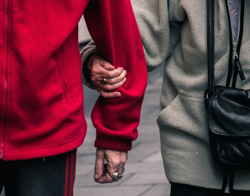 A man and women link arms and walk down the road together.