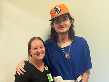 Clyde Blackburn wears a ball cap and stands with his arm draped over the shoulder of the woman next to him.