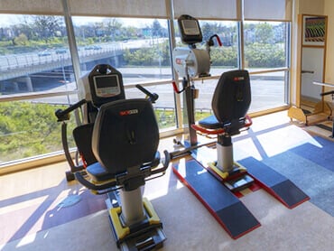 Stationary recumbant exercise bike and hand peddal equipment in a therapy gym.