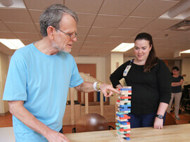 Male patient in blue t-shirt stacking small colored blocks on top of one another.